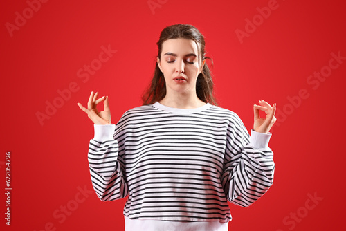 Bilde på lerret Meditating young woman on red background. Concept of self-control