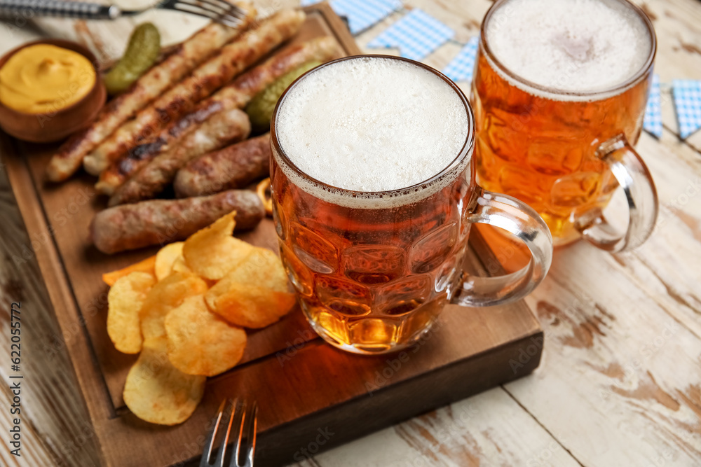 Mugs of cold beer and different snacks on light wooden background. Oktoberfest celebration Mugs of cold beer and different snacks on light wooden background. Oktoberfest celebration