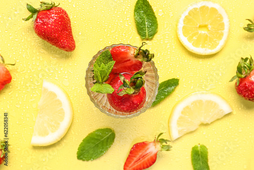 Fototapeta Naklejka Na Ścianę i Meble -  Glass of fresh lemonade with strawberry and lemon on yellow background