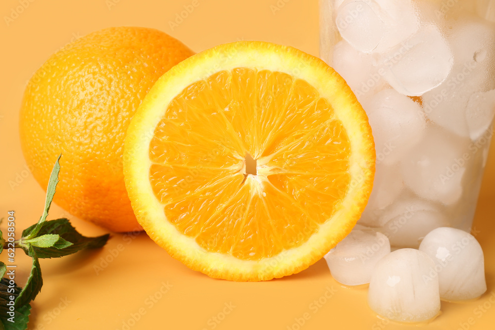 Glass of ice cubes with oranges and mint on color background Glass of ice cubes with oranges and mint on color background