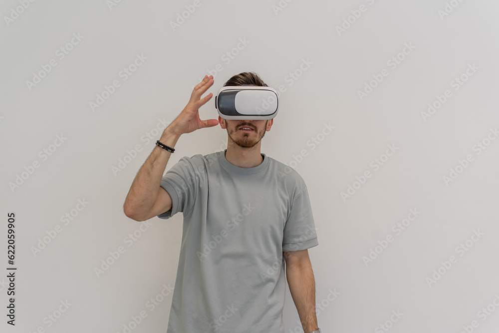 Futuristic man wearing virtual reality glasses interacts with the air in an isolated gray background. Futuristic man wearing virtual reality glasses interacts with the air in an isolated gray background.