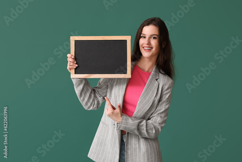 Female teacher pointing at chalkboard on green background