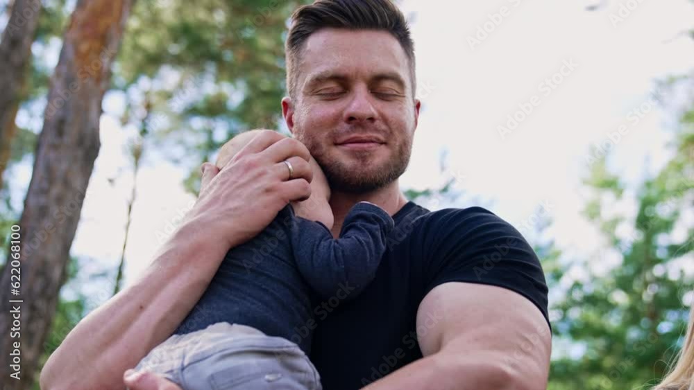 Muscular Caucasian bearded man holding his newborn son. Loving dad kisses his beloved son holding him tenderly. Muscular Caucasian bearded man holding his newborn son. Loving dad kisses his beloved son holding him tenderly.