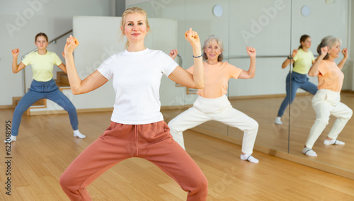 Middle aged adult athletic blonde woman dancing during group class in dance center