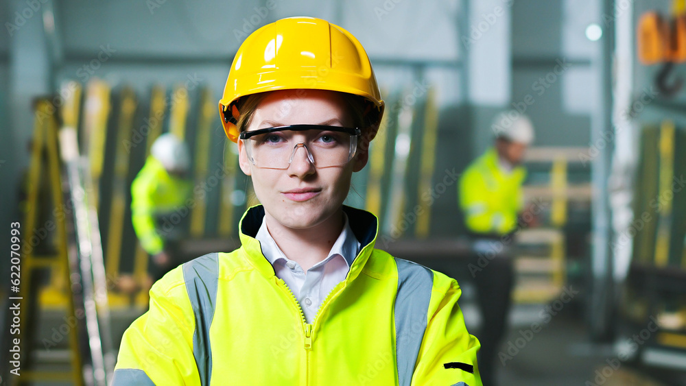 Portrait of beautiful Caucasian woman in helmet and uniform standing at plant manufactoring and taking on goggles. Indoors. Female worker at factory in hardhat and protectional glasses. Protection. Portrait of beautiful Caucasian woman in helmet and uniform standing at plant manufactoring and taking on goggles. Indoors. Female worker at factory in hardhat and protectional glasses. Protection.