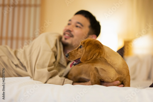 ホテルのベッドで飼い犬と戯れる男性