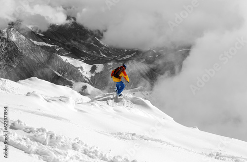 Snowboarder on off-piste slope and mountains in fog. Caucasus Mountains, Georgia, region Gudauri. Selective color.