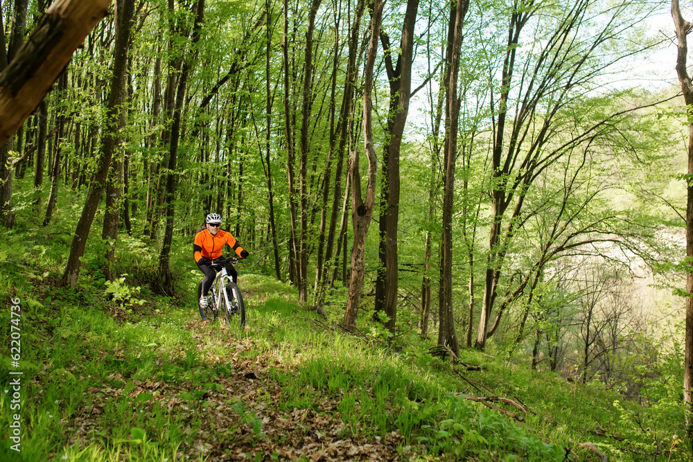 Biker in orange jersey on the forest road Biker in orange jersey on the forest road