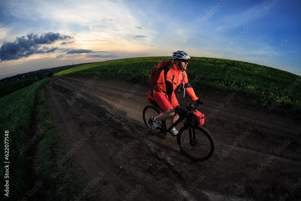 Man on mountain bike rides on the trail on a beautiful sunset. Wide view