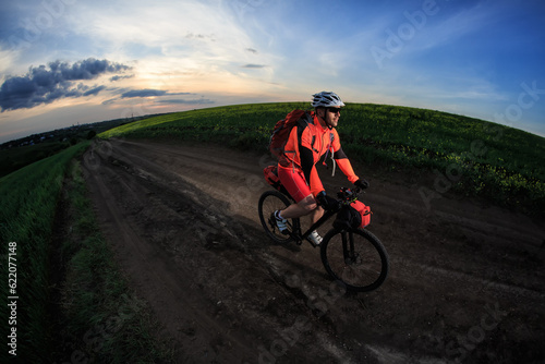 Man on mountain bike rides on the trail on a beautiful sunset. Wide view