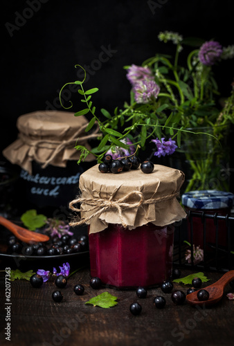 Jar of delicious homemade black currant curd (jam) on dark background