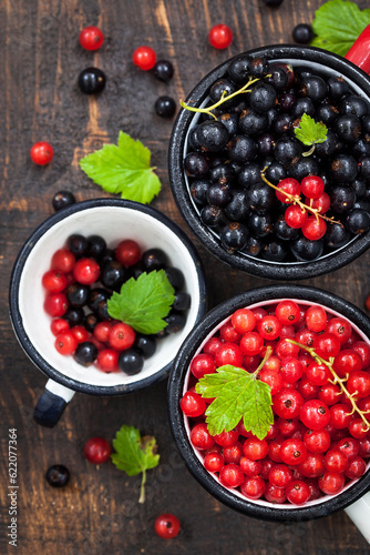 Fresh delicious organic red and black currants in a mugs on wooden table