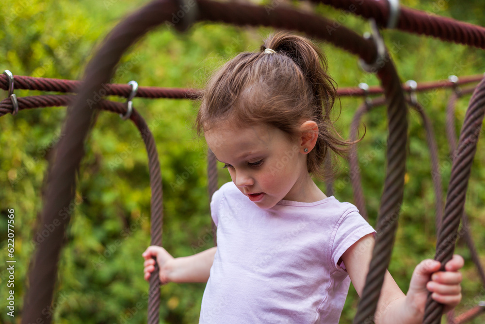 Adorable little girl having fun on a rope playground in the park Adorable little girl having fun on a rope playground in the park