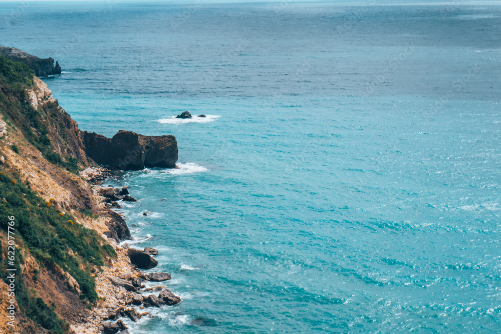 The azure sea against the backdrop of mountains and green trees The azure sea against the backdrop of mountains and green trees