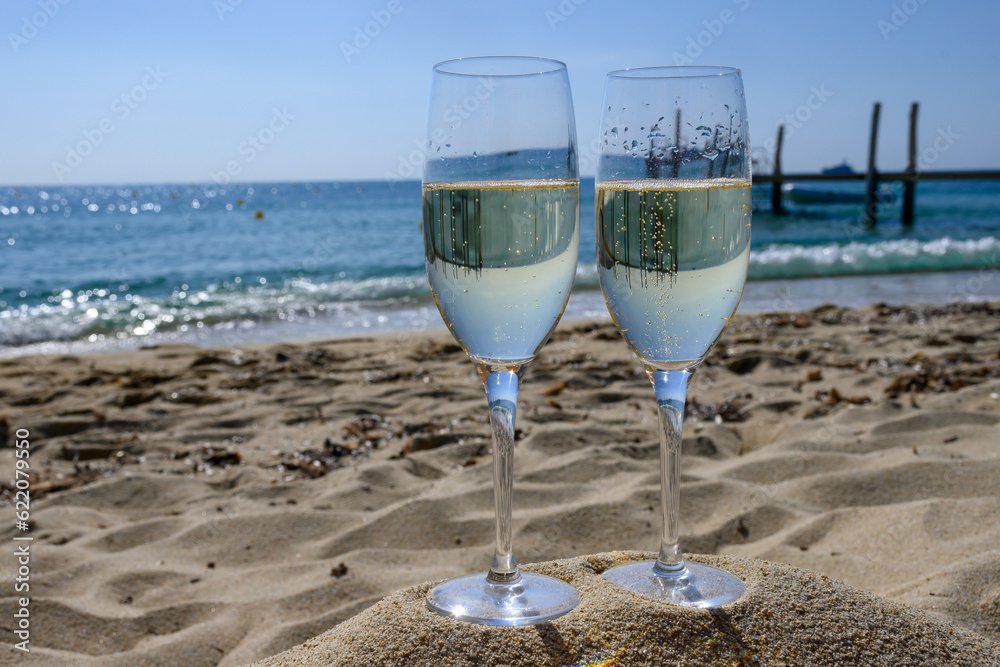 Summer time in Provence, two glasses of cold champagne cremant sparkling wine on famous Pampelonne sandy beach near Saint-Tropez in sunny day, Var department, France