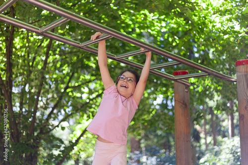 Little girl having fun on the playground at the day time. Concept of healthy lifestyle.