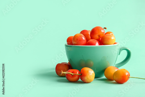 Fototapeta Naklejka Na Ścianę i Meble -  Cup with sweet yellow cherries on turquoise background