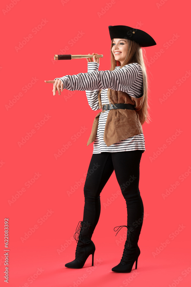 Beautiful female pirate with spyglass pointing at something on red background Beautiful female pirate with spyglass pointing at something on red background