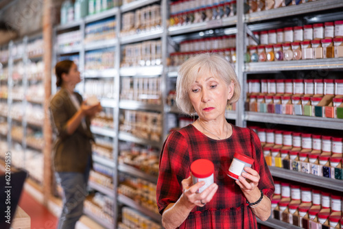 Elderly woman buys jars of paint and glaze to coat pottery at a ceramic specialty store