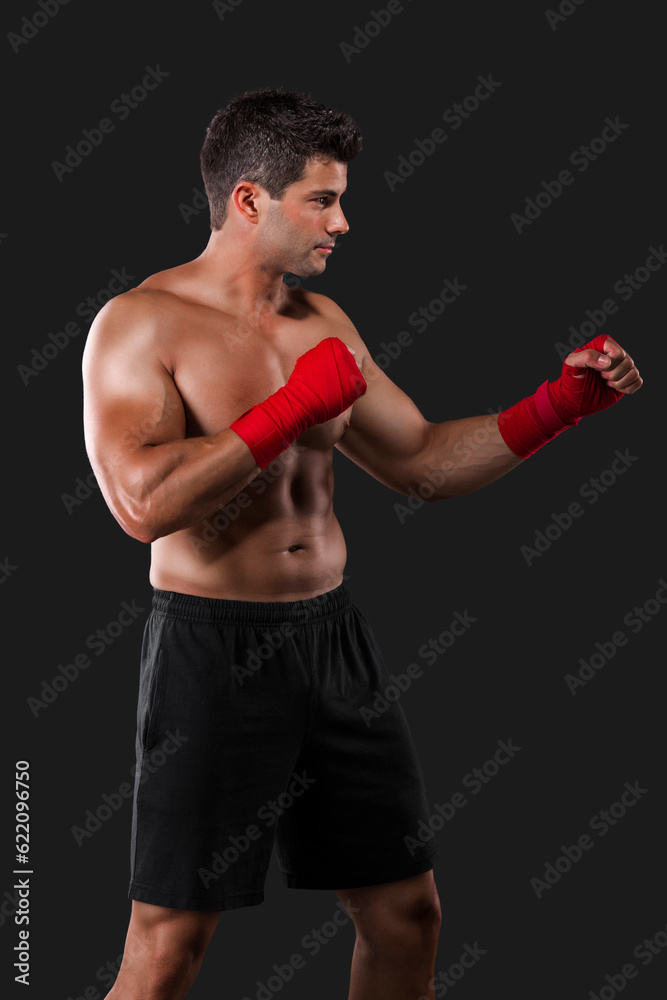 Portrait of a muscular man practicing body combat against a dark background