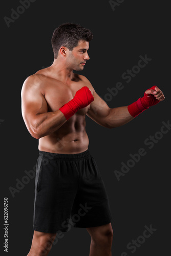 Portrait of a muscular man practicing body combat against a dark background © Designpics