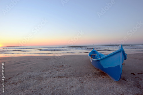 Sunrise on beach and blue boat