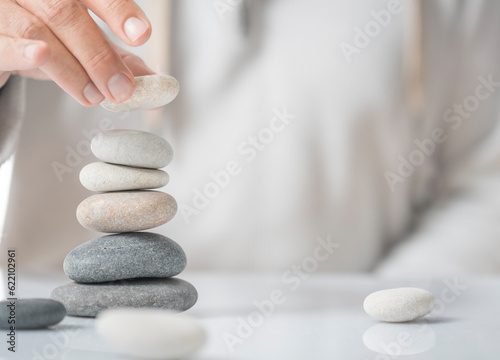 Fotografija Horizontal image of a man stacking pebbles on a table with copyspace for text