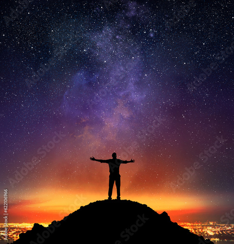 Businessman exults on a mountain with starry sky background
