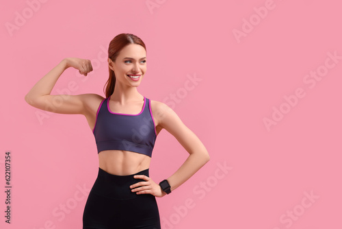 Young woman in sportswear showing muscles on pink background, space for text