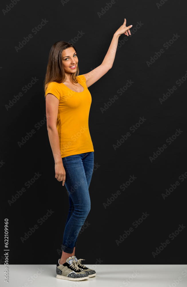 Beautiful woman standing in front of a dark board and pointing