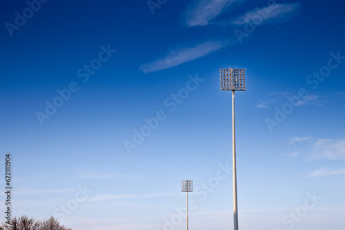 Stadium floodlights, used to lit a sports arena, also called reflectors or projectors, during a sunny afternoon. These are high consumers of power and energy.