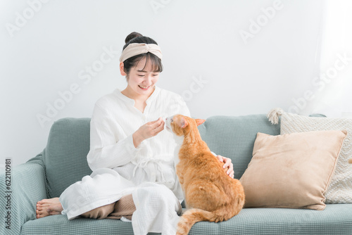 家・猫カフェで猫におやつをあげる日本人女性（餌） 