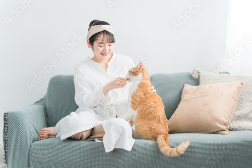 家・猫カフェで猫におやつをあげる日本人女性（餌） 