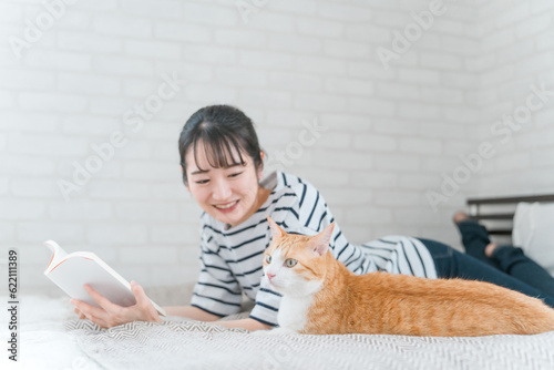 Fotografie, Obraz 家のベッドルームでペットの猫と遊ぶアジア人女性(読書・スキンシップ)