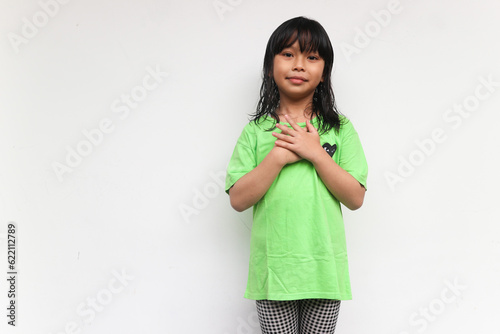A calm relaxed girl with a smiling face has a friendly expression, pressing her palm to chest. Love concept. close up portrait, relaxation, isolated white background