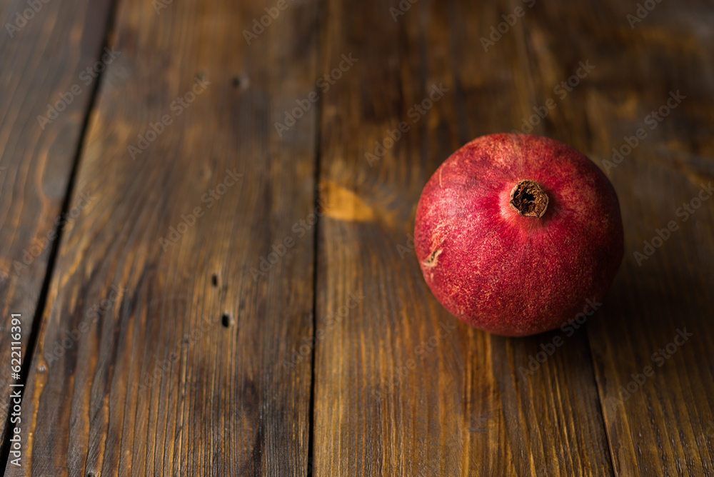 Red and ripe pomegranate lying on the wooden background. place for text. Red and ripe pomegranate lying on the wooden background. place for text.