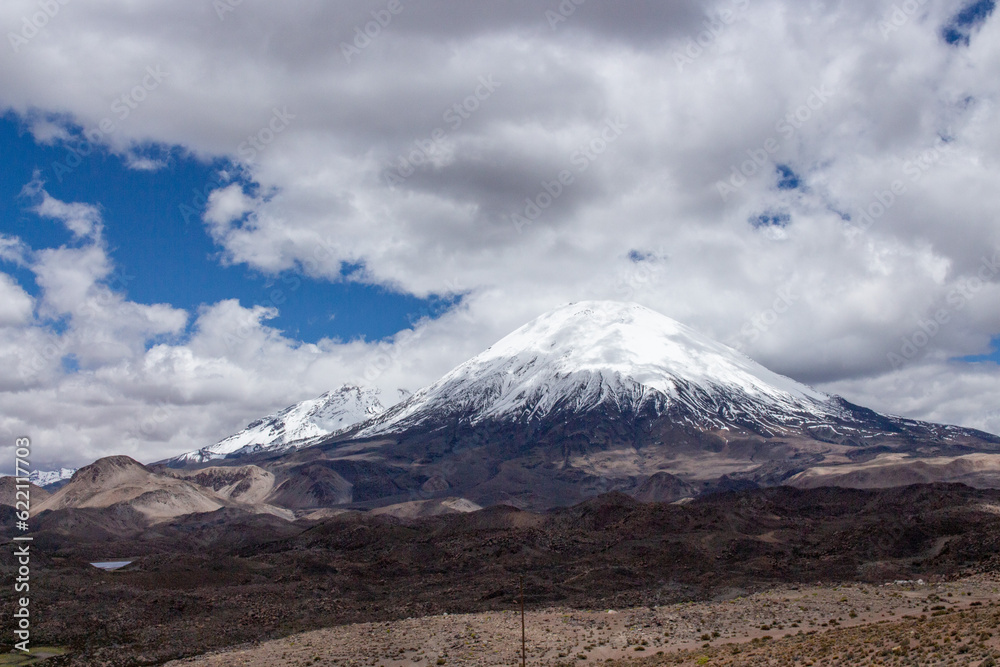 Parinacota volcano covered in snow, with rain clouds around it Parinacota volcano covered in snow, with rain clouds around it