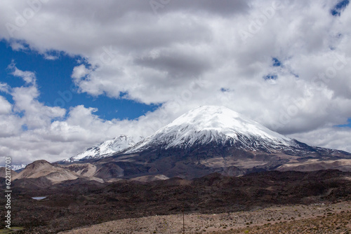 Parinacota volcano covered in snow, with rain clouds around it