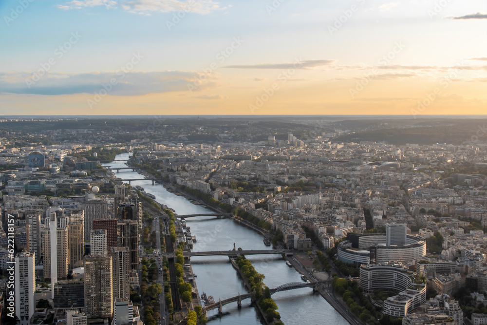 The Seine River flows through the heart of Paris, France, as seen from atop the Eiffel Tower during sunset.