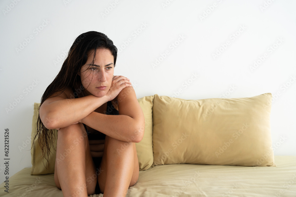 Brunette girl in bed with white background thinking with a blank stare Brunette girl in bed with white background thinking with a blank stare