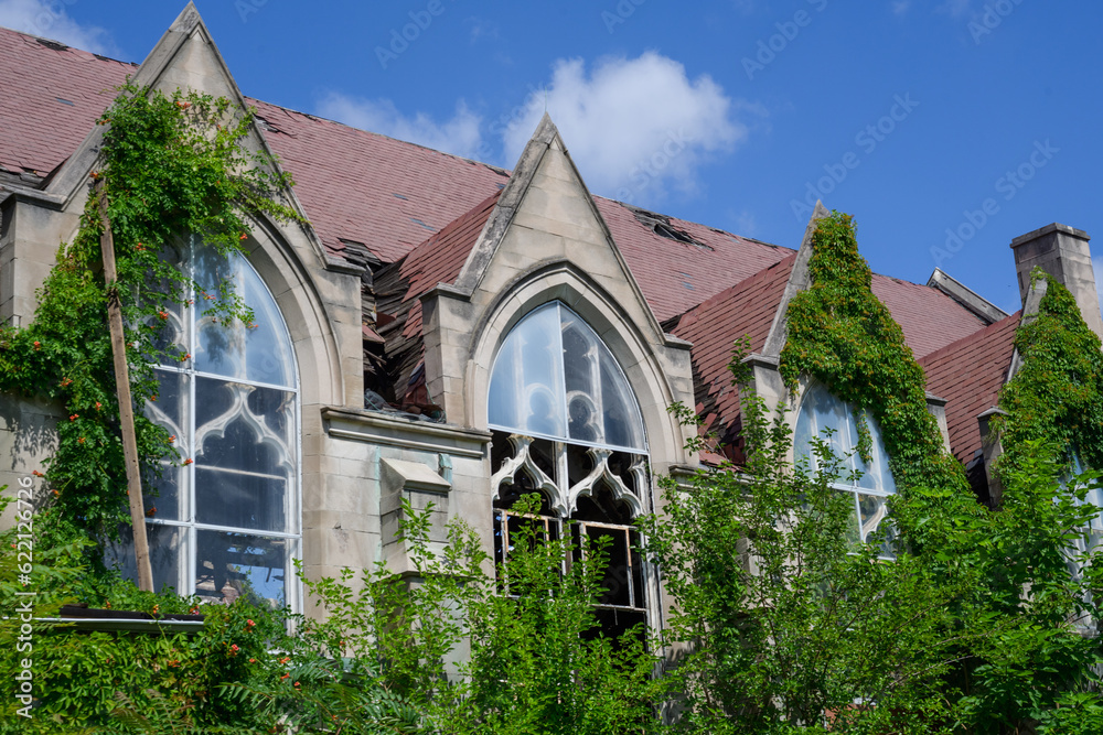 Abandoned Gothic Church with burned interior with blue clouds and vines growing up wall
