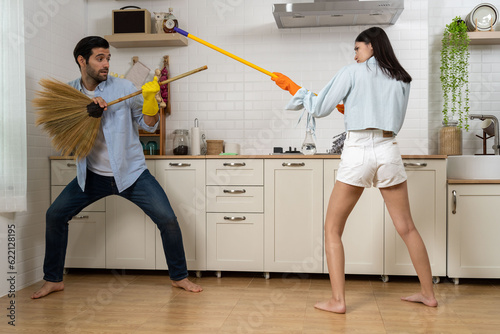 Young happy couple having fun while doing cleaning kitchen together