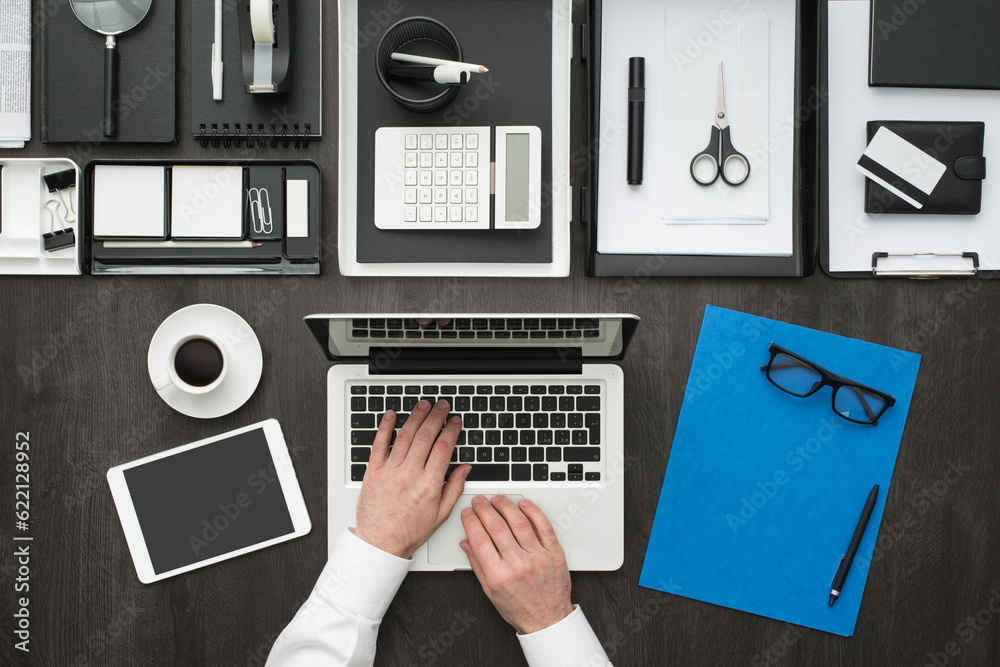 Corporate businessman working at office desk, he is networking with a laptop, flat lay