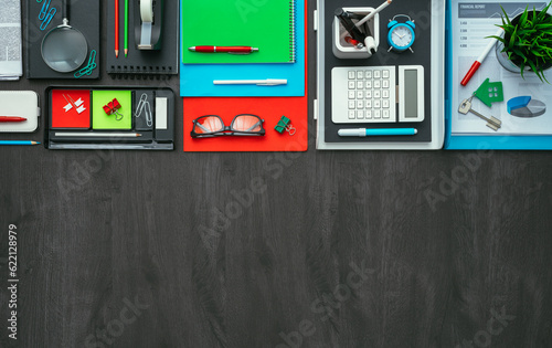 Creative business desktop with colorful office accessories and dark blank copy space, flat lay
