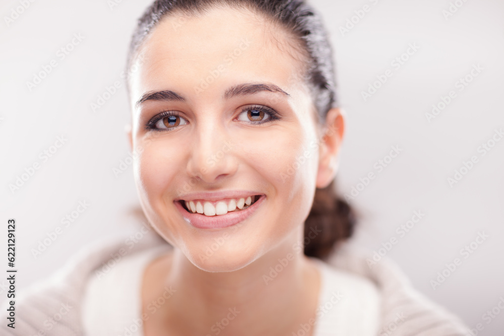 Cheerful young woman smiling at camera and showing her perfect face skin Cheerful young woman smiling at camera and showing her perfect face skin