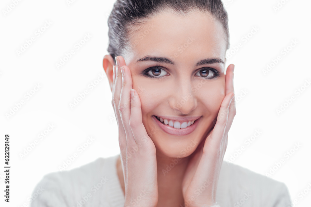 Beautiful female model touching her smooth glowing face skin and smiling at camera Beautiful female model touching her smooth glowing face skin and smiling at camera