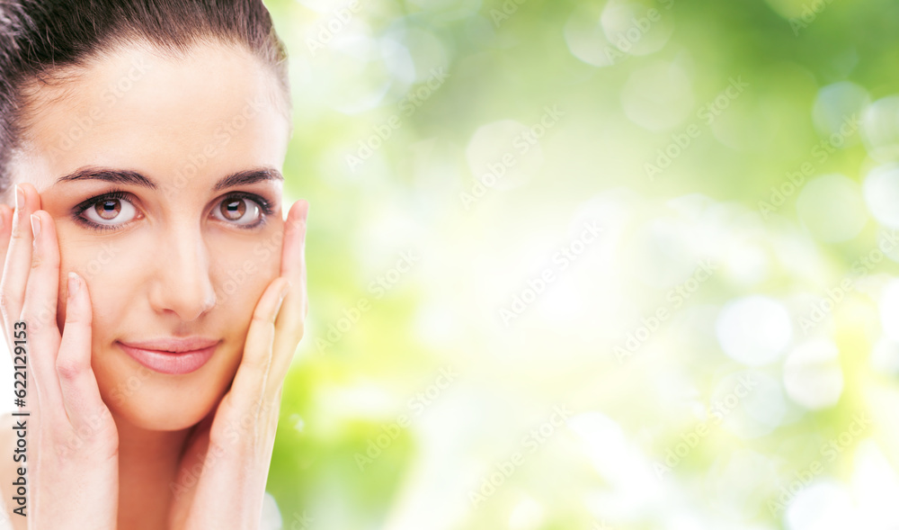 Beautiful female model touching her smooth glowing face skin and smiling at camera Beautiful female model touching her smooth glowing face skin and smiling at camera