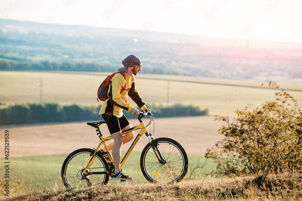 Mountain Bike cyclist riding single track above sunset valley against blue sky