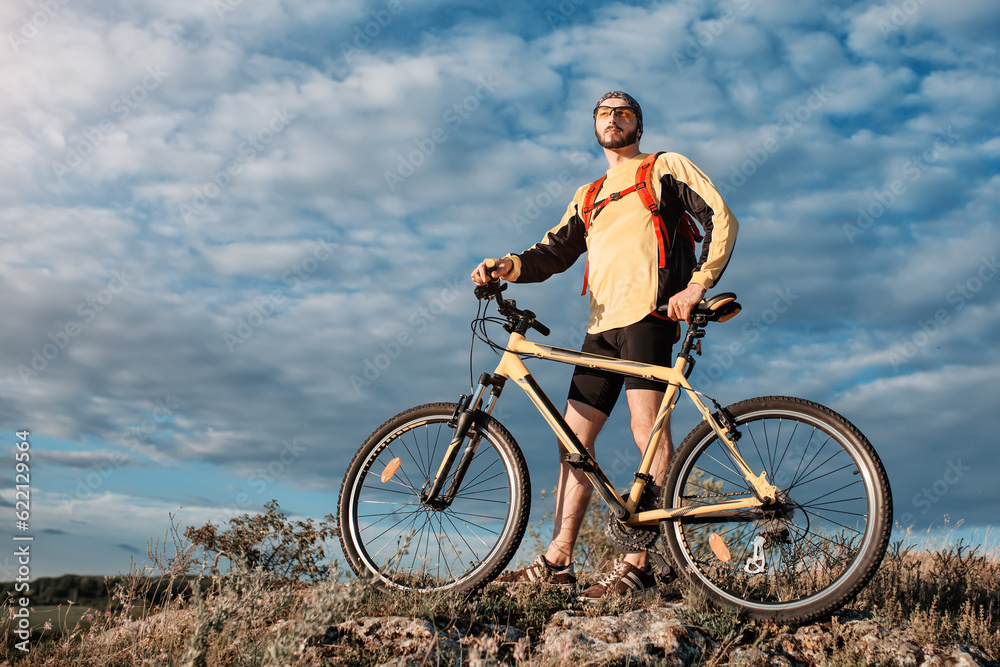 Mountain Bike cyclist riding single track above sunset valley against blue sky Mountain Bike cyclist riding single track above sunset valley against blue sky