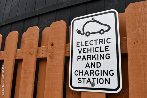 Electric vehicle parking and charging station sign on wooden fence. photo